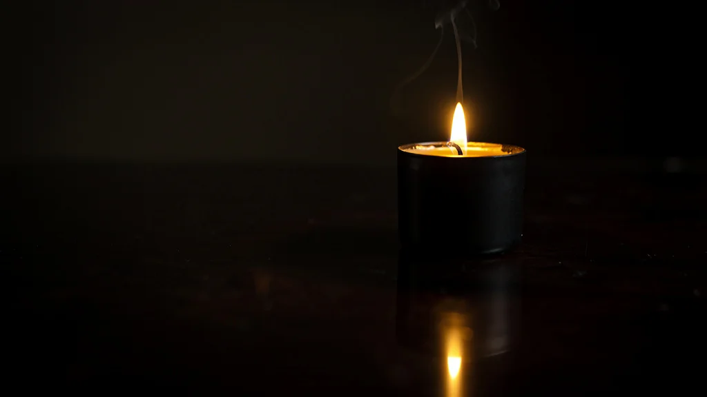 A single lit candle glowing softly in a dark room with warm tones