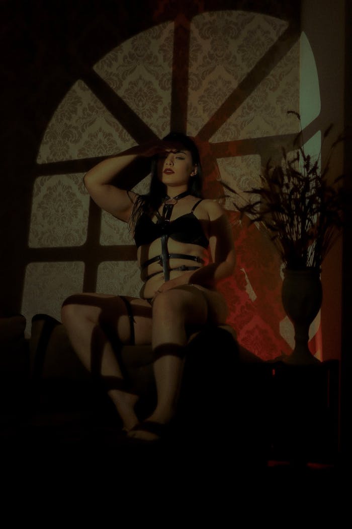 services-01 Artistic shot of a woman in fetish wear with dramatic shadows indoors.